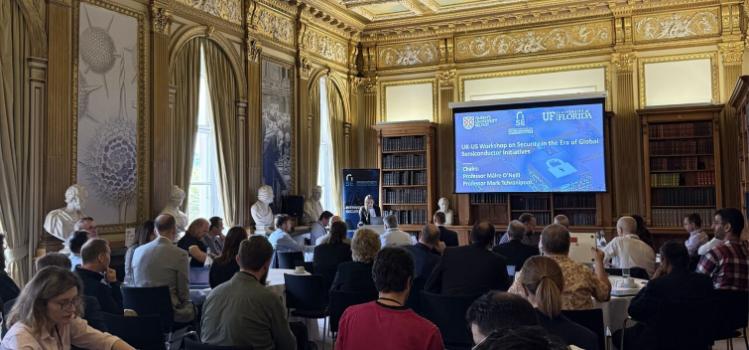 A group of people sitting in an ornately decorated conference room, attending semiconductor symposium 2025